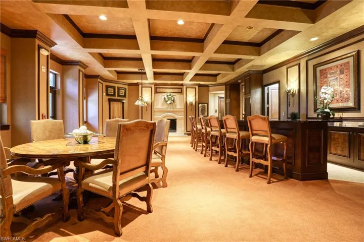 Dining area featuring light colored carpet, beam ceiling, ornamental molding, and coffered ceiling