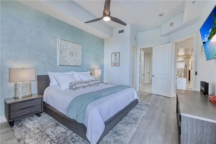 Bedroom with ensuite bathroom, ceiling fan, and light wood-type flooring