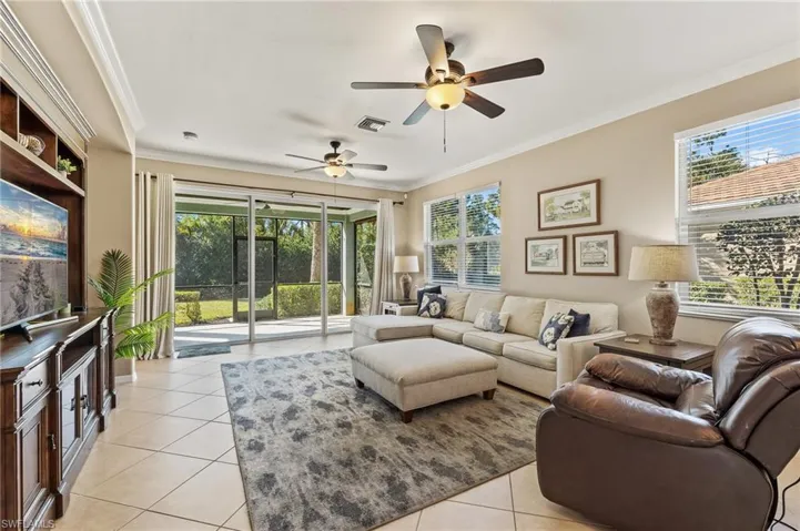 Living room with crown molding, light tile patterned floors, a ceiling fan, and healthy amount of natural light