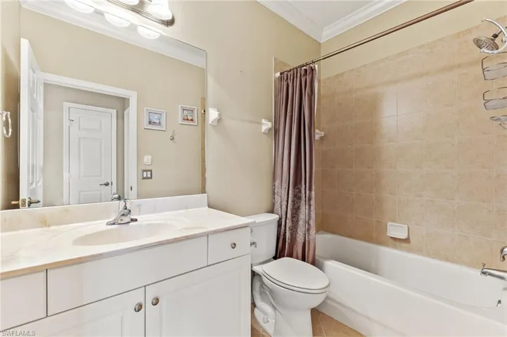 Full bath featuring ornamental molding, shower / bathtub combination with curtain, vanity, and light tile patterned floors