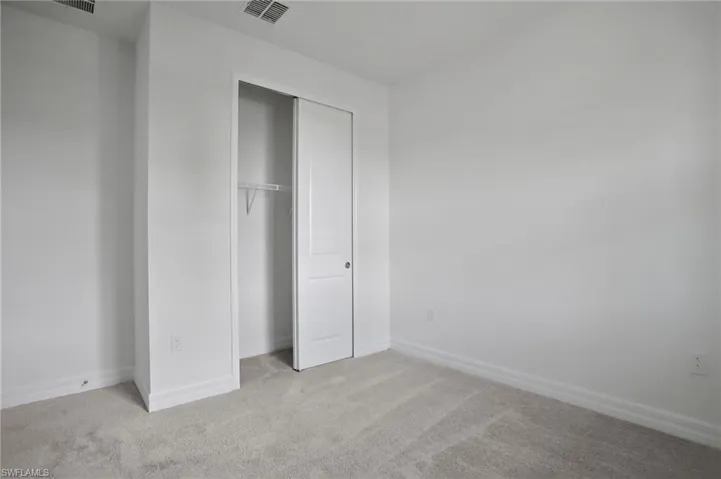 Unfurnished bedroom with light carpet and a closet