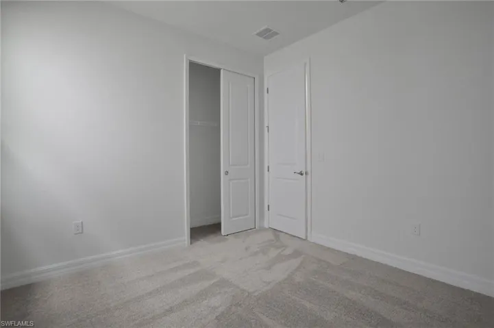 Unfurnished bedroom featuring light colored carpet and a closet
