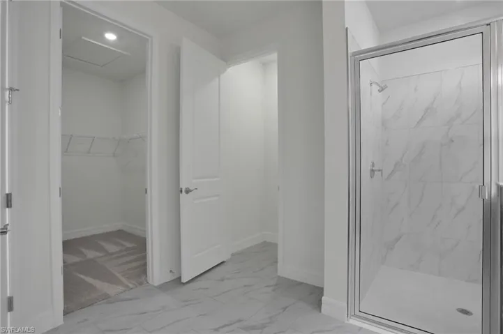 Full bathroom with light marble finish flooring, a marble finish shower, a walk in closet, and recessed lighting