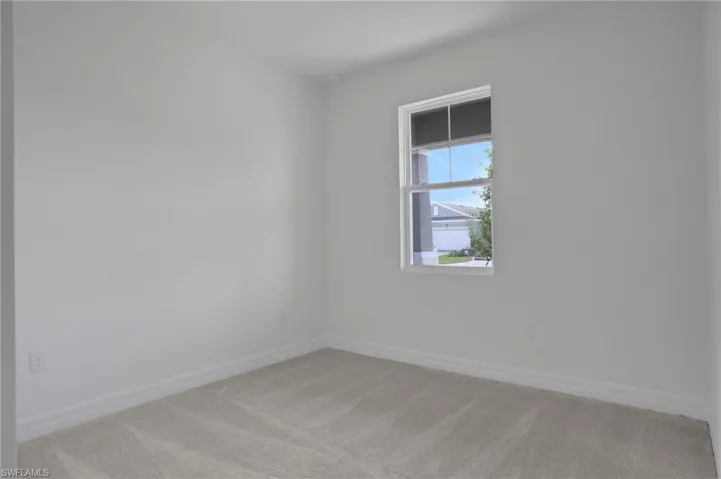Empty room featuring light carpet and baseboards