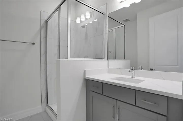 Full bathroom featuring a marble finish shower, vanity, and light marble finish floors