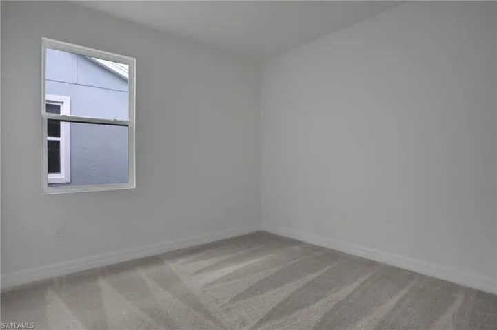 Empty room featuring light colored carpet and baseboards