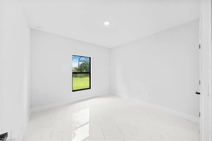Recessed ceiling lighting, a single window with black trim, and light-toned tile flooring