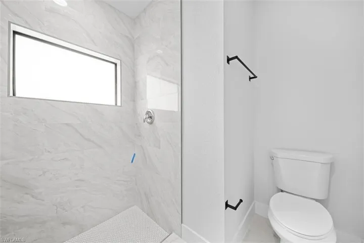 Walk-in shower with large format tile surround, horizontal accent window, and coordinating mosaic tile flooring