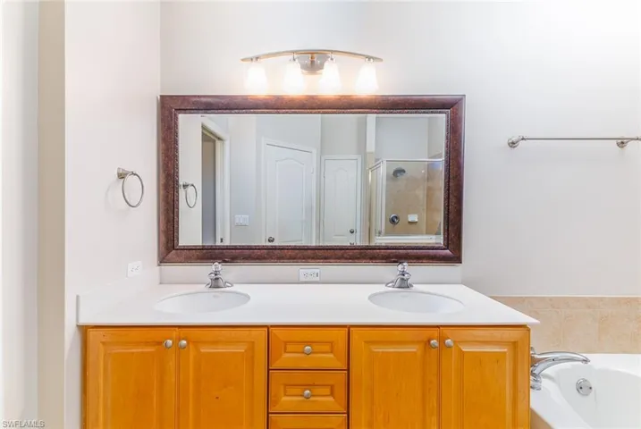 Bathroom featuring vanity with extensive cabinet space, separate shower and tub, and dual sinks