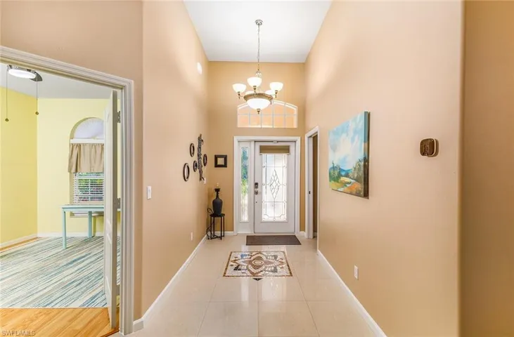 Tiled entryway featuring a chandelier and a towering ceiling
