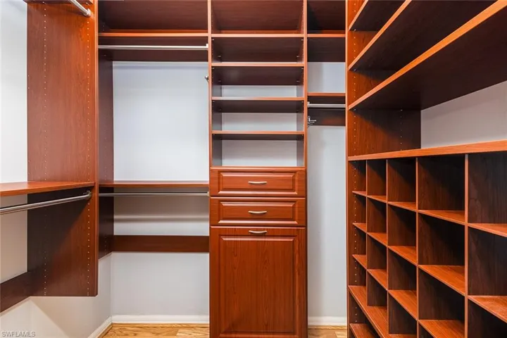 Spacious master closet with custom shelving featuring light hardwood style flooring