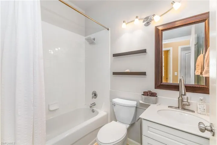 Full guest bathroom featuring shower / bathtub combination with curtain, crown molding, vanity, and toilet