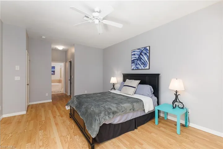 Bedroom featuring en-suite bathroom, ceiling fan, and hardwood style floors