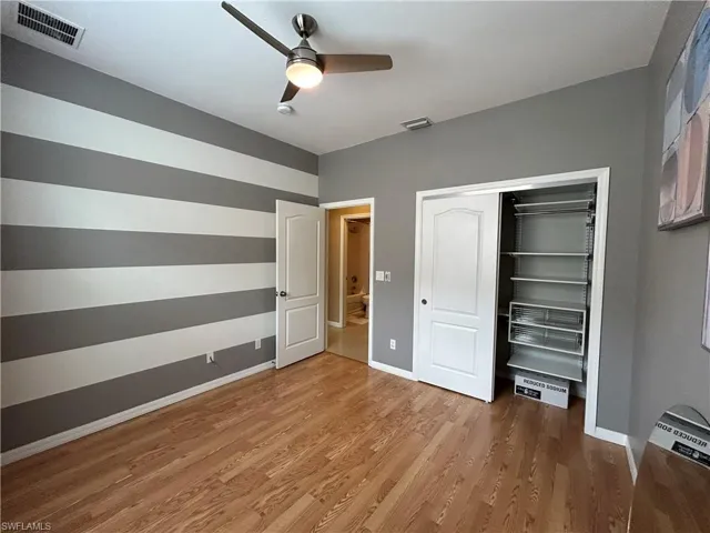 Bedroom 2 with custom shelving closet and hardwood style flooring