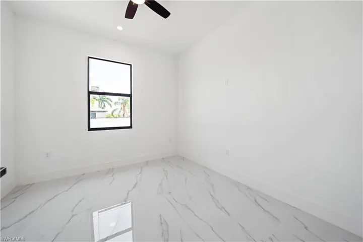Spacious room featuring white walls, white baseboards, and large-format tile flooring with a marble-effect pattern