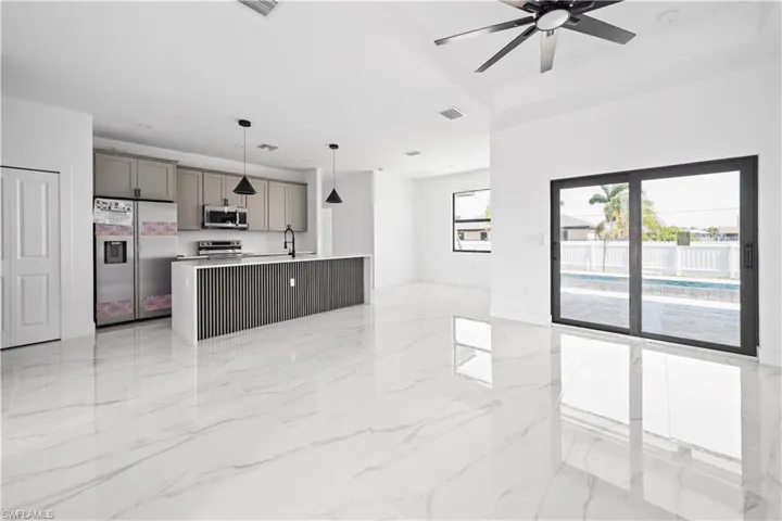 Open-concept living area featuring large format polished tile flooring and a kitchen island with a slatted wood-finish panel