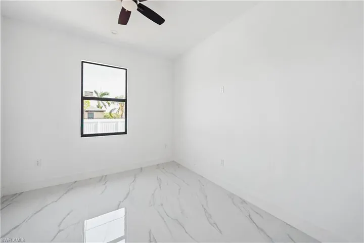 Room featuring a black framed window, white walls, and marble-look tile flooring