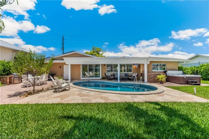 View of pool with a patio, an outdoor hangout area, a hot tub, and a lawn