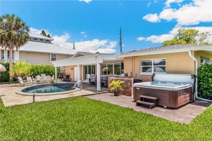 Back of property with a patio area, a hot tub, and a lawn