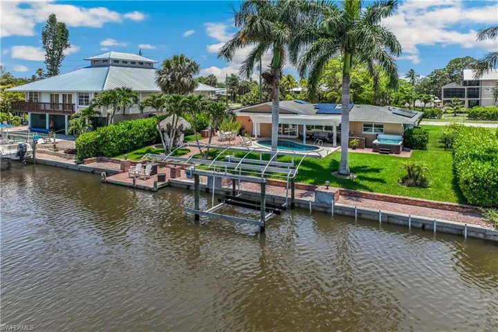Dock area featuring a water view, a patio area, and a lawn