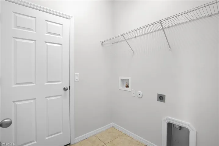 Dedicated utility space featuring tile flooring, white baseboards, and a paneled interior door