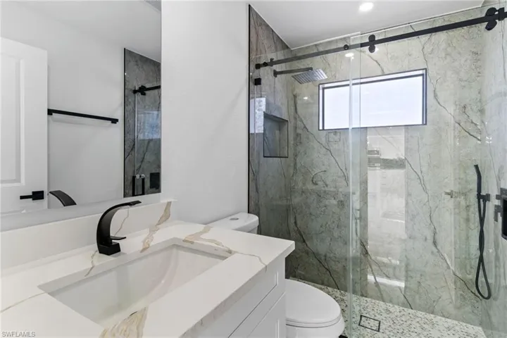 Bathroom with vanity and a marble finish shower