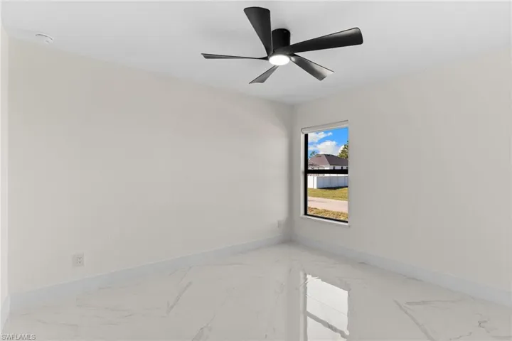 Spare room featuring light marble finish floors and ceiling fan