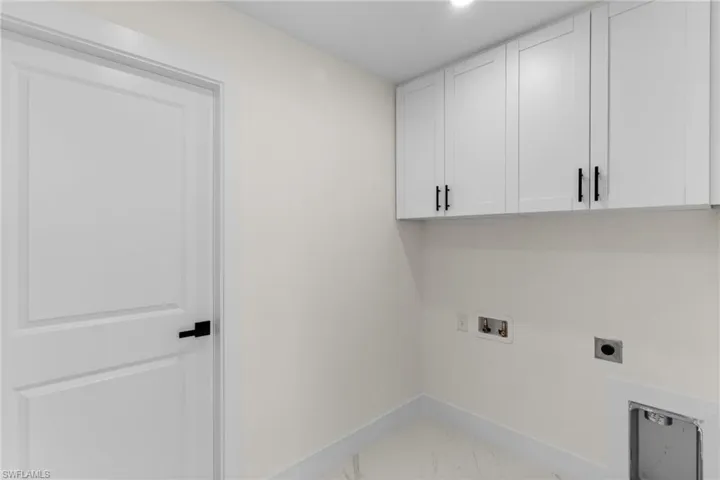 Laundry area with light marble finish flooring, hookup for a washing machine, cabinet space, and electric dryer hookup