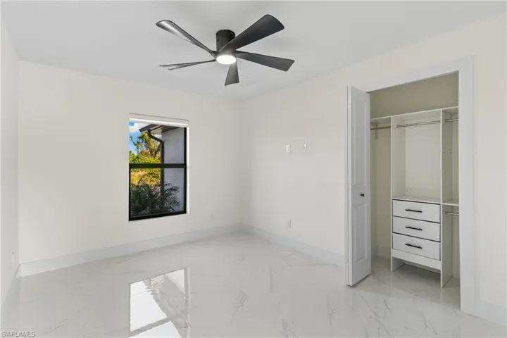 Unfurnished bedroom with light marble finish flooring, ceiling fan, and a closet