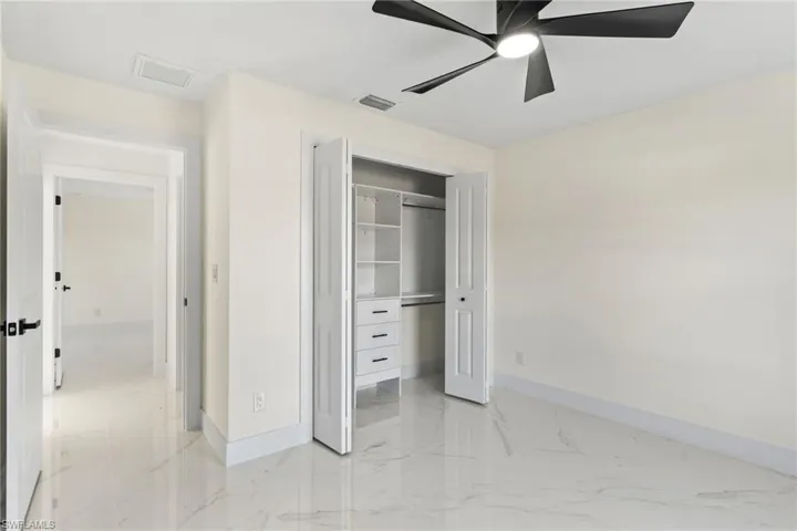Unfurnished bedroom with a closet, a ceiling fan, and light marble finish flooring