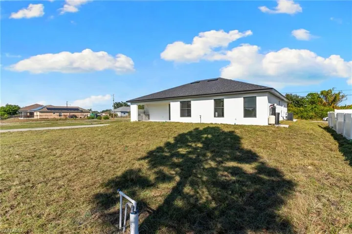 Back of property with a lawn and stucco siding