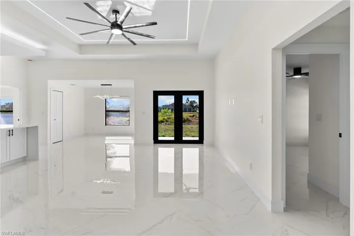 Entryway with ceiling fan, light marble finish flooring, and a tray ceiling