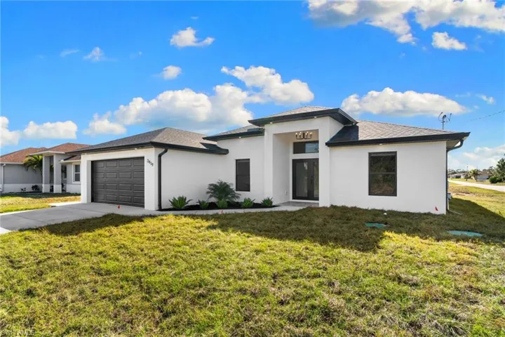Prairie-style home featuring a front lawn, stucco siding, driveway, and a garage
