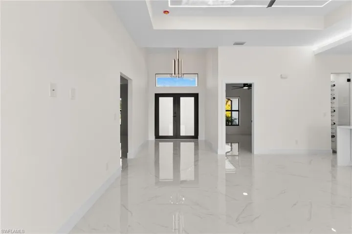 Foyer featuring a high ceiling, light marble finish floors, a ceiling fan, and a tray ceiling