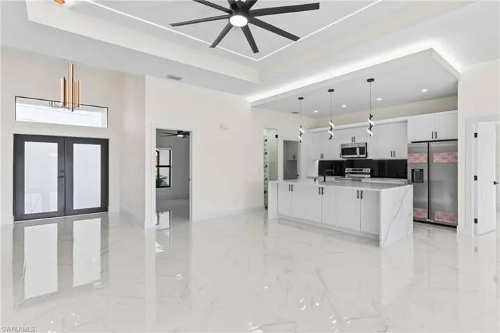 Kitchen featuring pendant lighting, ceiling fan, white cabinetry, stainless steel appliances, and open floor plan
