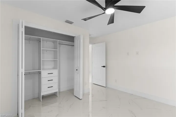 Unfurnished bedroom featuring light marble finish floors, a closet, and ceiling fan