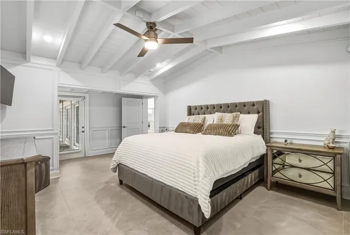 Bedroom featuring a decorative wall, a wainscoted wall, and ceiling fan