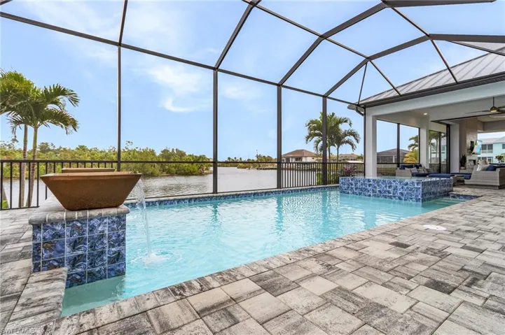 View of swimming pool featuring pool water feature, a lanai, a water view, and a patio