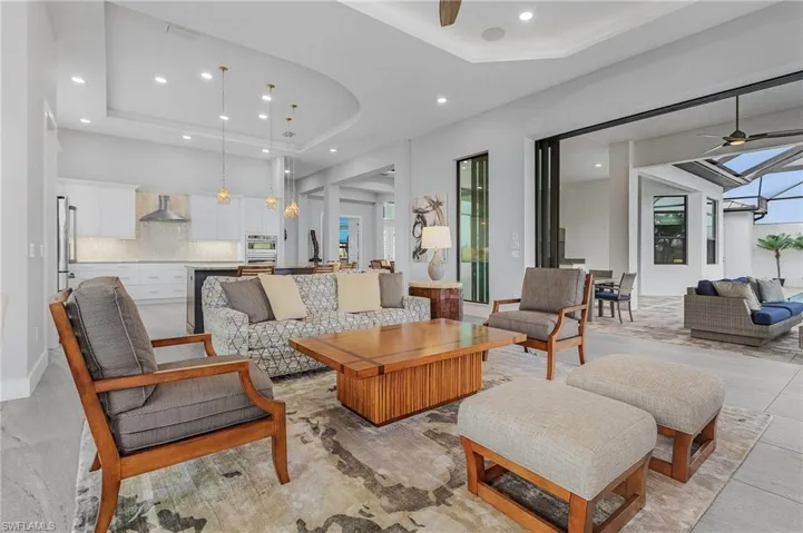 Living room with a tray ceiling, a wealth of natural light, and ceiling fan