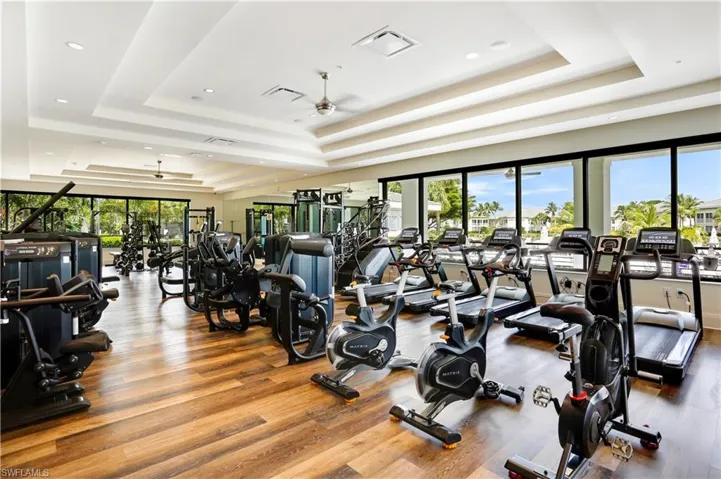Gym featuring a tray ceiling, plenty of natural light, a ceiling fan, and recessed lighting