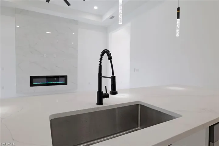 Room details featuring light stone countertops, sink, pendant lighting, and a high end fireplace