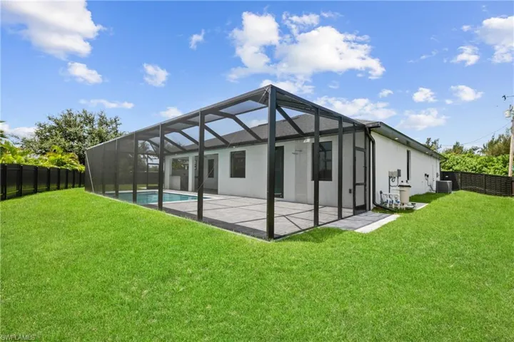 Rear view of house with a yard, a patio area, a lanai, and cooling unit