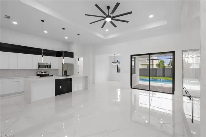 Kitchen featuring white cabinetry, a raised ceiling, appliances with stainless steel finishes, and pendant lighting