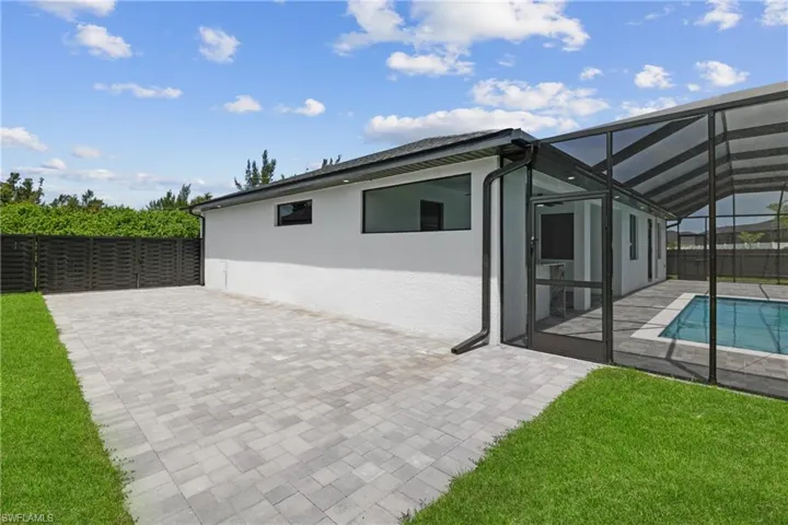 Rear view of house featuring a yard, a patio area, a fenced in pool, and a lanai