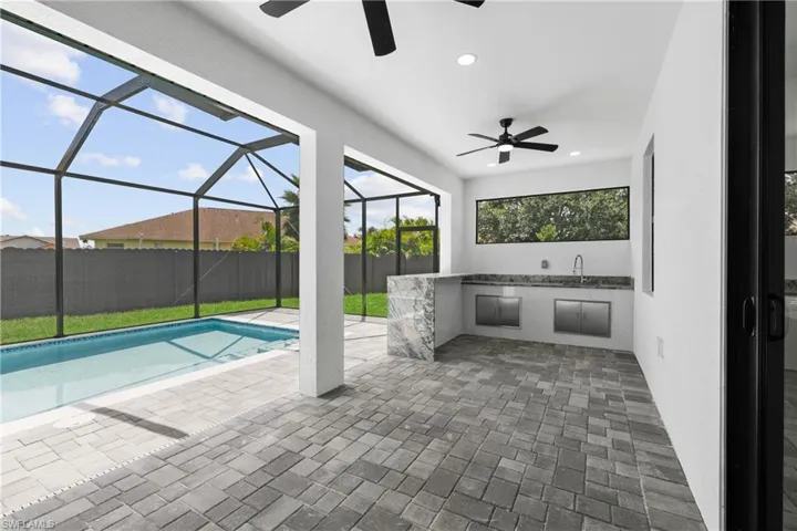 View of pool featuring a patio area, glass enclosure, sink, and ceiling fan