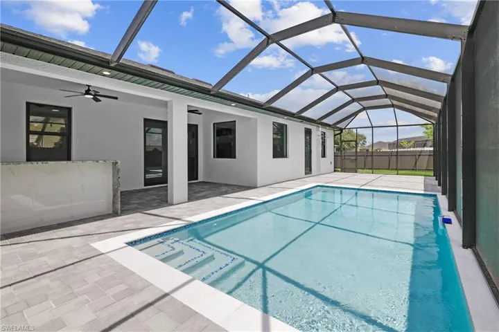 View of swimming pool featuring a patio area, glass enclosure, and ceiling fan