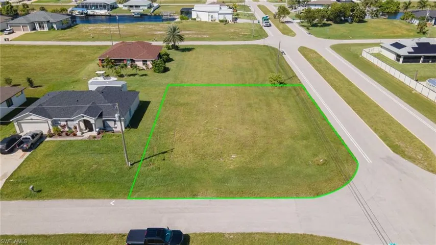Aerial view of residential area with property boundaries highlighted and a nearby body of water