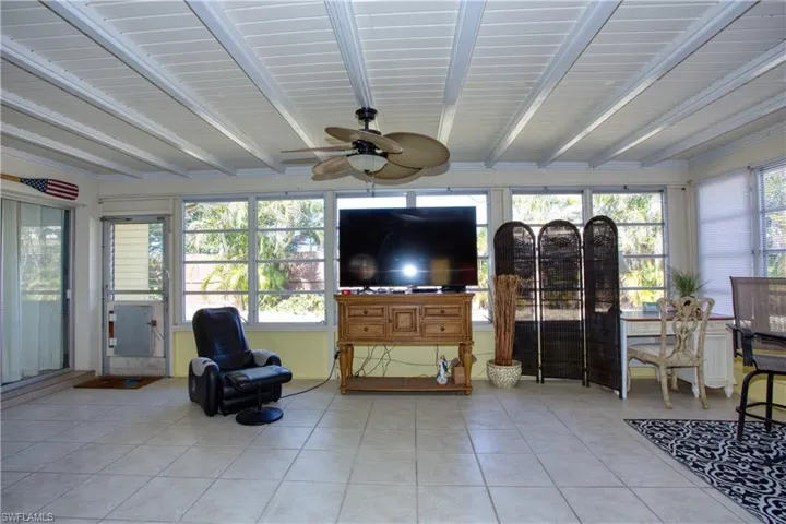 Sunroom / solarium featuring ceiling fan and beam ceiling