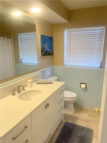 Full bathroom featuring vanity, curtained shower, tile walls, and a wainscoted wall