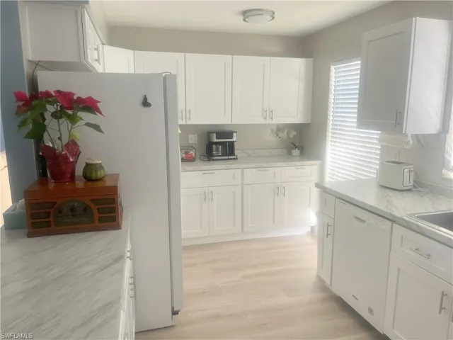 Kitchen featuring white cabinetry, white appliances, healthy amount of natural light, and light wood-type flooring